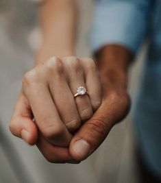 a close up of a person holding the hand of another person with a ring on their finger