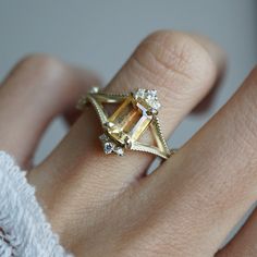 a woman's hand with a diamond ring on top of her finger and an orange stone in the middle