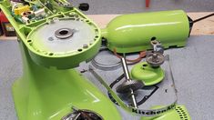 a green blender sitting on top of a floor next to other appliances and tools