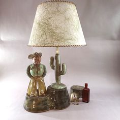 a lamp that is on top of a table next to a cactus and a bottle