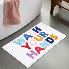 a bathroom rug with the words wash your hands on it and a bathtub in the background