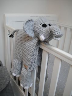 a crocheted elephant stuffed animal hanging from the side of a crib