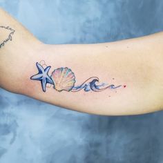 a woman's arm with a starfish and seashell tattoo on it