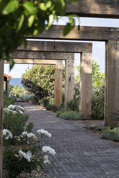 the walkway is lined with white flowers and wooden posts that lead into an open area