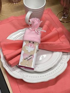 a pink table cloth and napkins on a white plate with a cup in the background