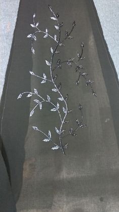 an embroidered piece of cloth with white flowers on black fabric, sitting on the ground