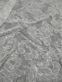 an image of a white lace fabric with flowers on it's side and the top half