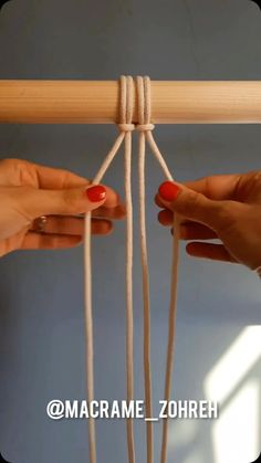 two hands are pulling strings from the top of a wooden pole to another person's hand