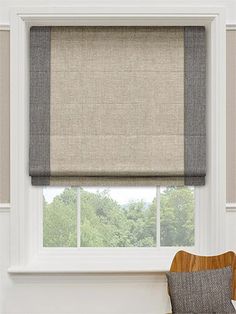 a chair sitting in front of a window with a roman blind on top of it