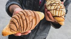 two people holding pastries in their hands with peanut butter and chocolate toppings on them