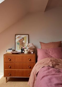 a bedroom with a bed, dresser and window in the corner next to an attic