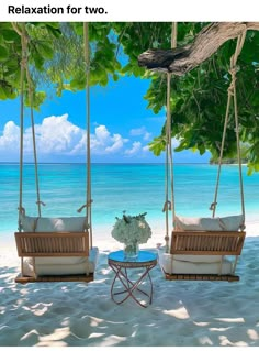 two wooden swing chairs sitting on top of a sandy beach