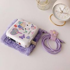 an electronic device sitting on top of a purple blanket next to a clock and other items