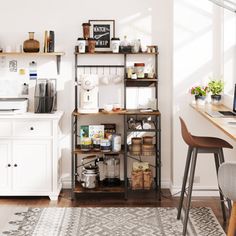 a kitchen area with a desk, computer and shelves filled with items on top of it