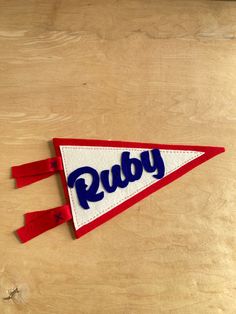 a red, white and blue pennant with the word ruby on it sitting on a wooden surface