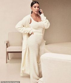 a woman in a white robe talking on a cell phone while standing next to a couch