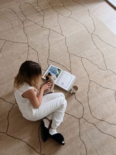 a woman sitting on the floor reading a book