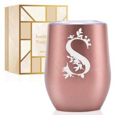 a rose gold stemless wine glass with the letter s etched on it next to a gift box