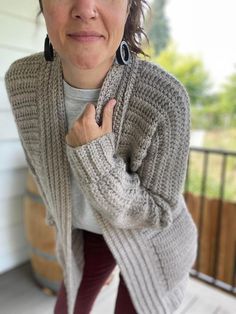 a woman standing on the porch with her hand in her pocket and looking at the camera