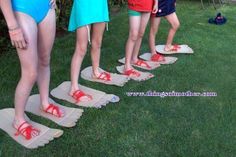 four young children standing in the grass wearing swimsuits and flip flops on their feet