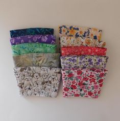 five different colored flowered cloths are lined up on a white surface with one folded and the other unzipped