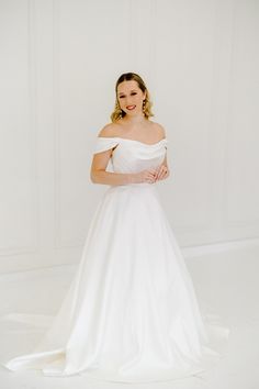 a woman in a white wedding dress posing for the camera with her hands on her hips