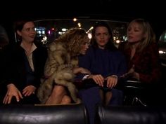 three women sitting in the back of a car talking to each other while one woman looks on