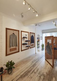 the inside of a clothing store with wooden floors and pictures on the wall above them