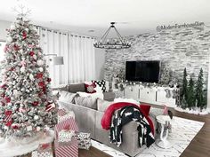 a living room decorated for christmas with white and red decorations on the walls, a large tree in the corner