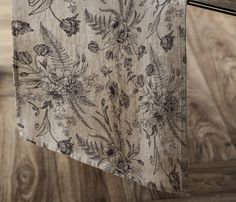 a close up of a table cloth with flowers and leaves on it, hanging from a metal rod