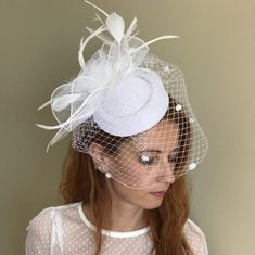 This is a handcrafted felt wedding fascinator hat, with flower looking tulle, delicate feathers, and birdcage veil. The color is white, goes with common wedding dress colors. Burgundy color is also available for this listing. It is made in a standard one-size, and it has a hair clip under it for easy wearing on any hair style. This model and other models are available in various colors, check them out from here: https://www.etsy.com/shop/ArtisanTulipBridal?section_id=44269044 Perfect to accentua Adjustable Wedding Hat With Feather Trim, Spring Wedding Feathered Fascinator, Spring Wedding Feather Fascinator, Spring Wedding Fascinator With Feathers, Adjustable Feather Trim Wedding Headpieces, Wedding Costume Hats With Feather Trim, Feathered Headband Hat For Wedding, Summer Wedding Fascinator With Feathers, Feathered Mini Hats For Wedding And Kentucky Derby