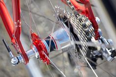 the front wheel of a bicycle with red spokes and gear on it's side