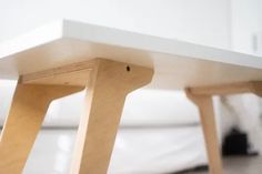 a wooden bench sitting on top of a hard wood floor next to a white couch