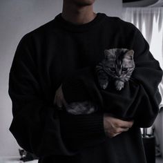 a man holding a cat in his arms while wearing a sweater and hat with the image of a cat on it's chest