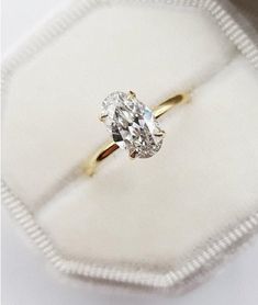 an oval cut diamond ring in a white velvet box