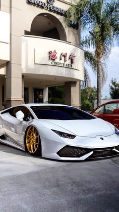 a white sports car parked in front of a building with gold rims on it