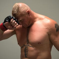 a shirtless man holding a pair of boxing gloves on his left hand and looking down