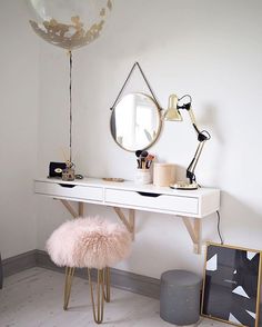 a white desk with a mirror, stool and lamp on it in a small room