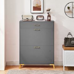 a grey cabinet with two drawers and a purse on top next to a white wall