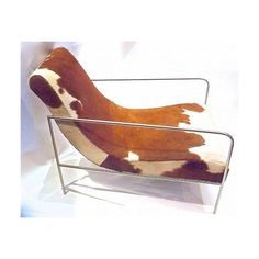 a brown and white cow print chair sitting on top of a metal frame with legs