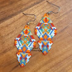 a pair of beaded earrings sitting on top of a wooden table