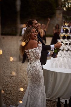 a man and woman standing next to each other in front of a table with wine glasses