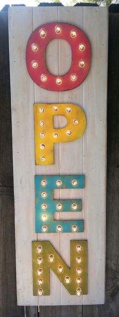 a wooden sign that has lights on the letters p and f in different colors hanging from it's sides