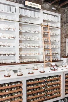 the shelves are filled with many different kinds of jars and cups in glass cases, along with a ladder