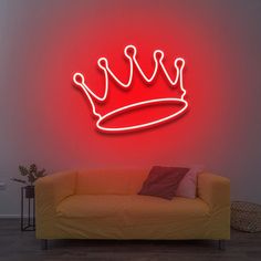 a red neon sign with a crown on it's wall next to a couch