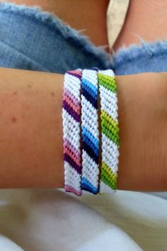 a woman's arm with three bracelets made from different colors of yarn and thread