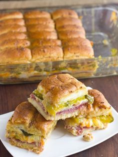 two sandwiches cut in half on a plate next to a casserole dish full of them