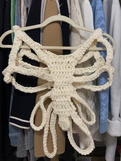 a crocheted octopus is hanging on a clothes hanger in front of some shirts