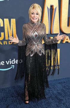 dolly on the red carpet at the cma awards wearing a black fringe dress and matching heels