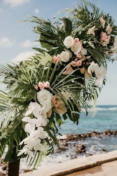 flowers and greenery are arranged on the beach